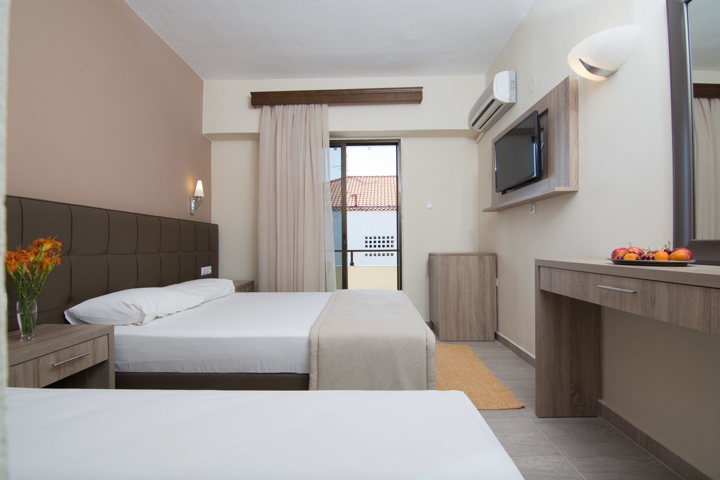Hotellihuone, jossa on sänky, yöpöytä, televisio ja näkymä ulos.