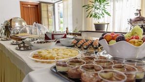 A buffet with various food items and a fruit bowl. - Sun Rise Hotel (Aristotelis)