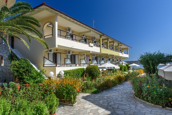 A multi-story hotel with balconies, outdoor seating, and a landscaped garden.