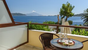 A balcony with a table set for two, overlooking a body of water and a mountain. - Sun Rise Hotel (Aristotelis)