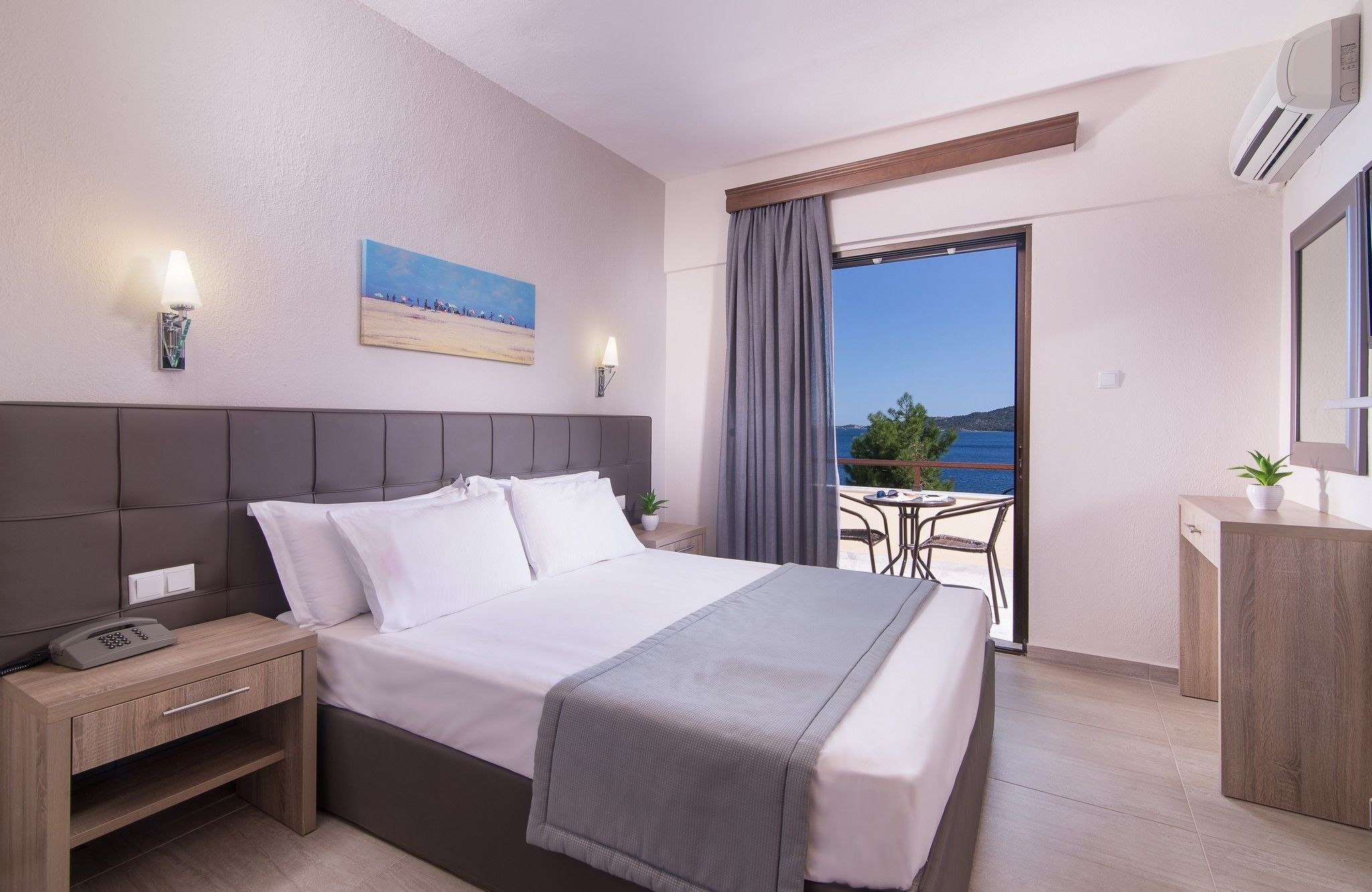 A hotel room with a bed, bedside table, and a view of the sea.