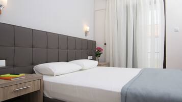 A hotel room with a large bed, a nightstand, a lamp, and a window with curtains.