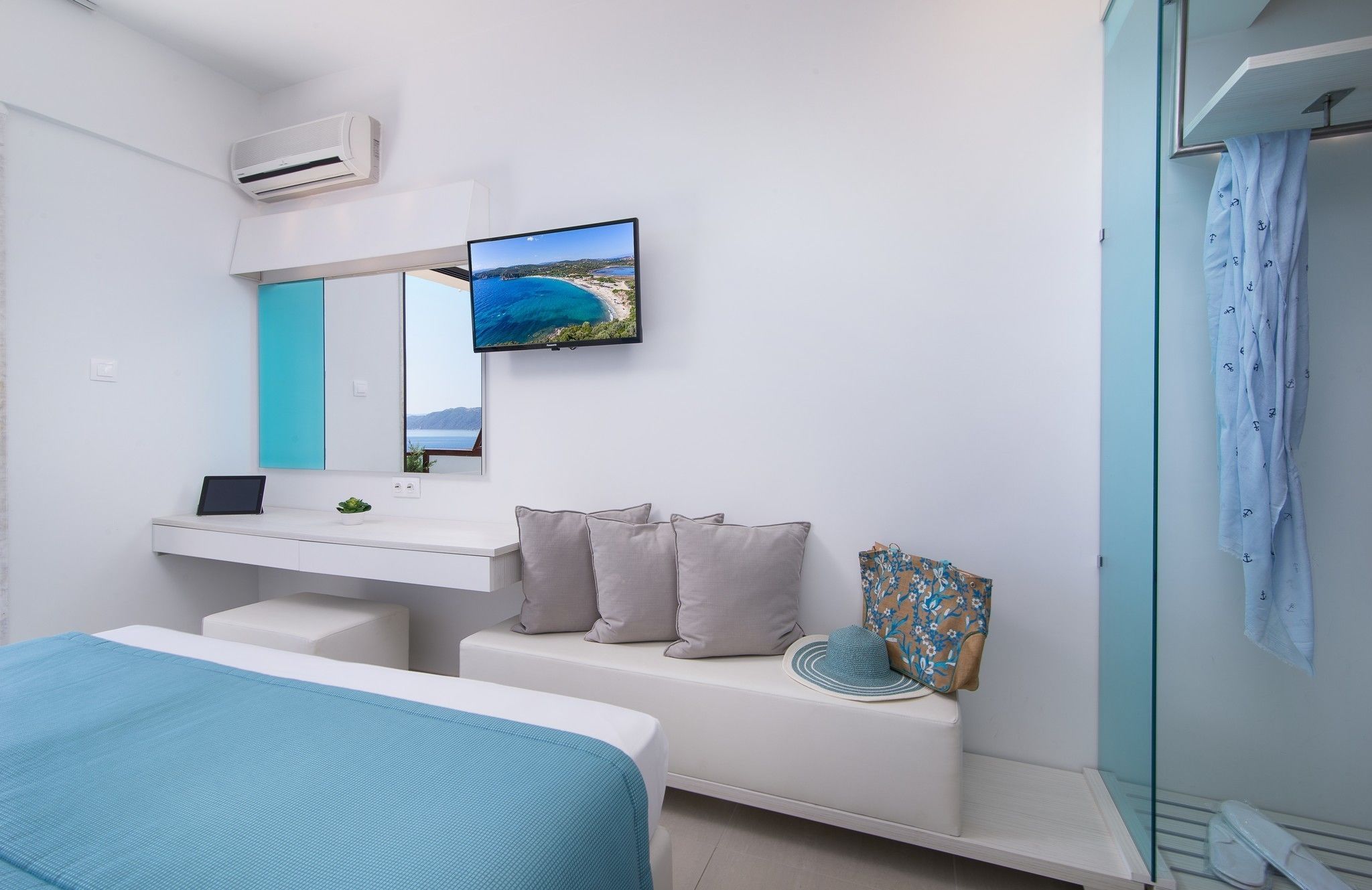 Un dormitorio moderno con cama, escritorio, televisión y baño con cortina de ducha.