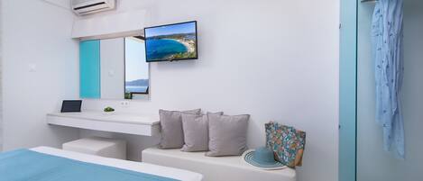 Un dormitorio moderno con cama, escritorio, televisión y baño con cortina de ducha.