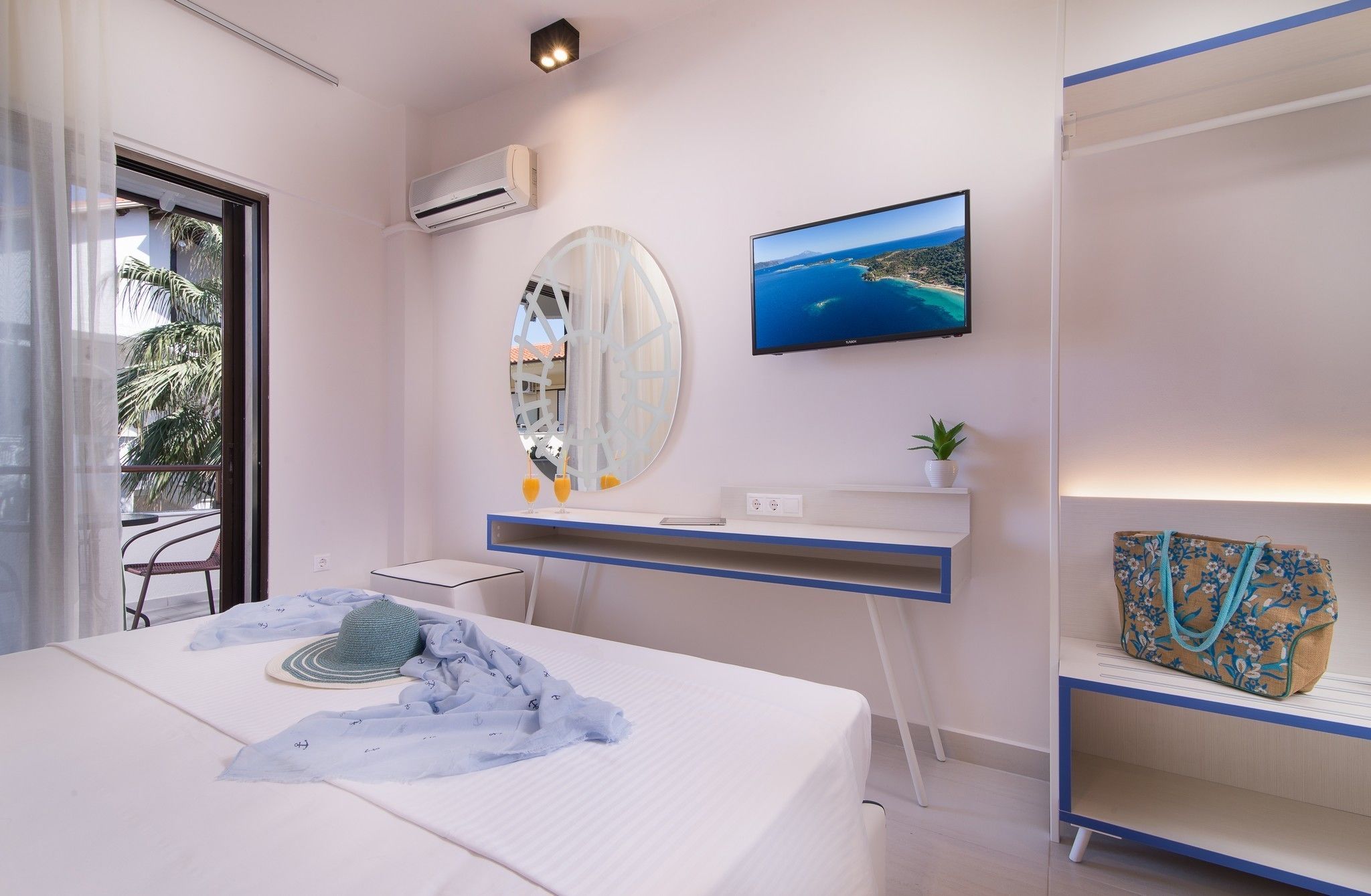 Una habitación de hotel moderna con una cama, un escritorio con computadora, un televisor y vista al mar.