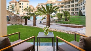 A hotel courtyard with a pool, palm trees, and a view of the building.