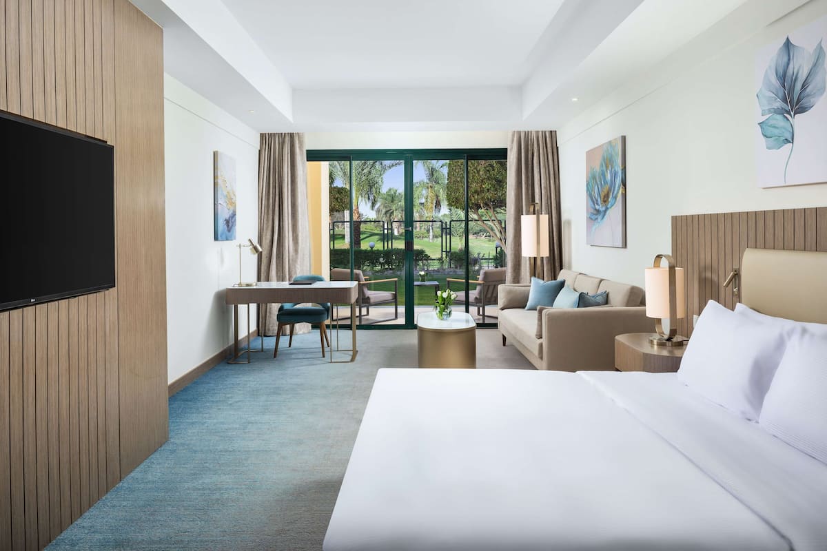 A hotel room with a bed, a desk, a sofa, a coffee table, and a TV.