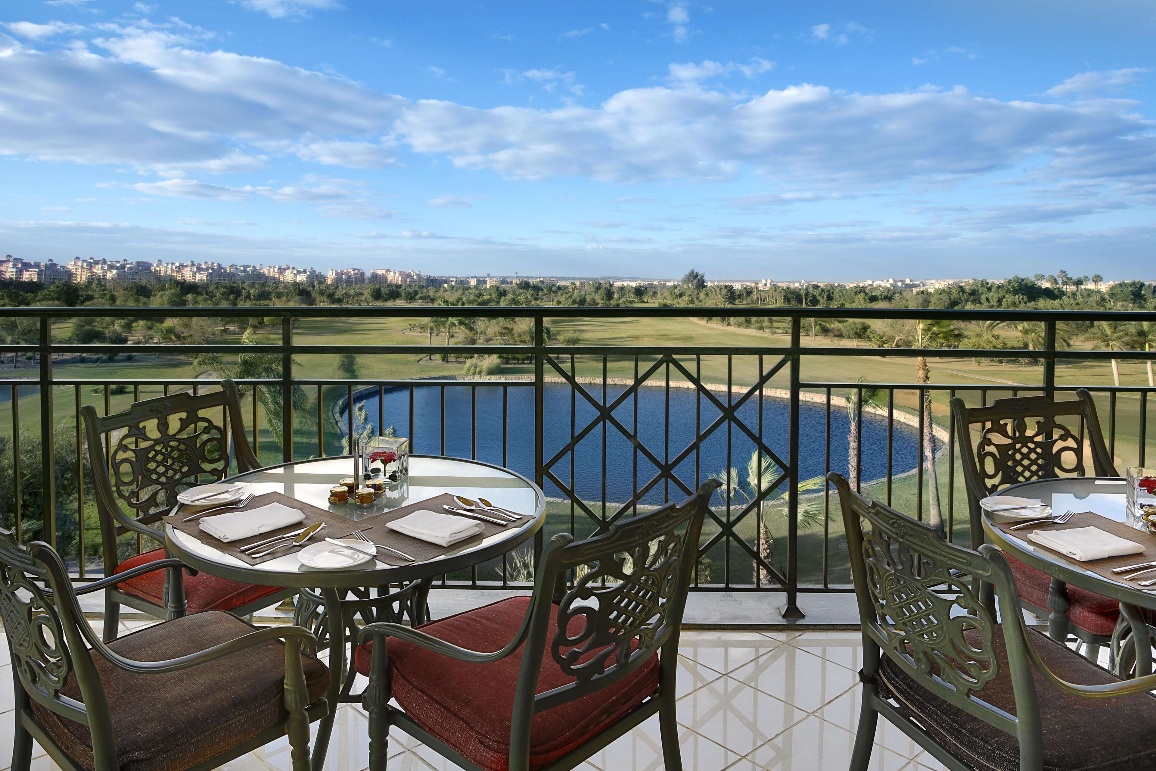 Un balcón con una mesa lista para comer, con vistas a un campo de golf y una extensión de agua.