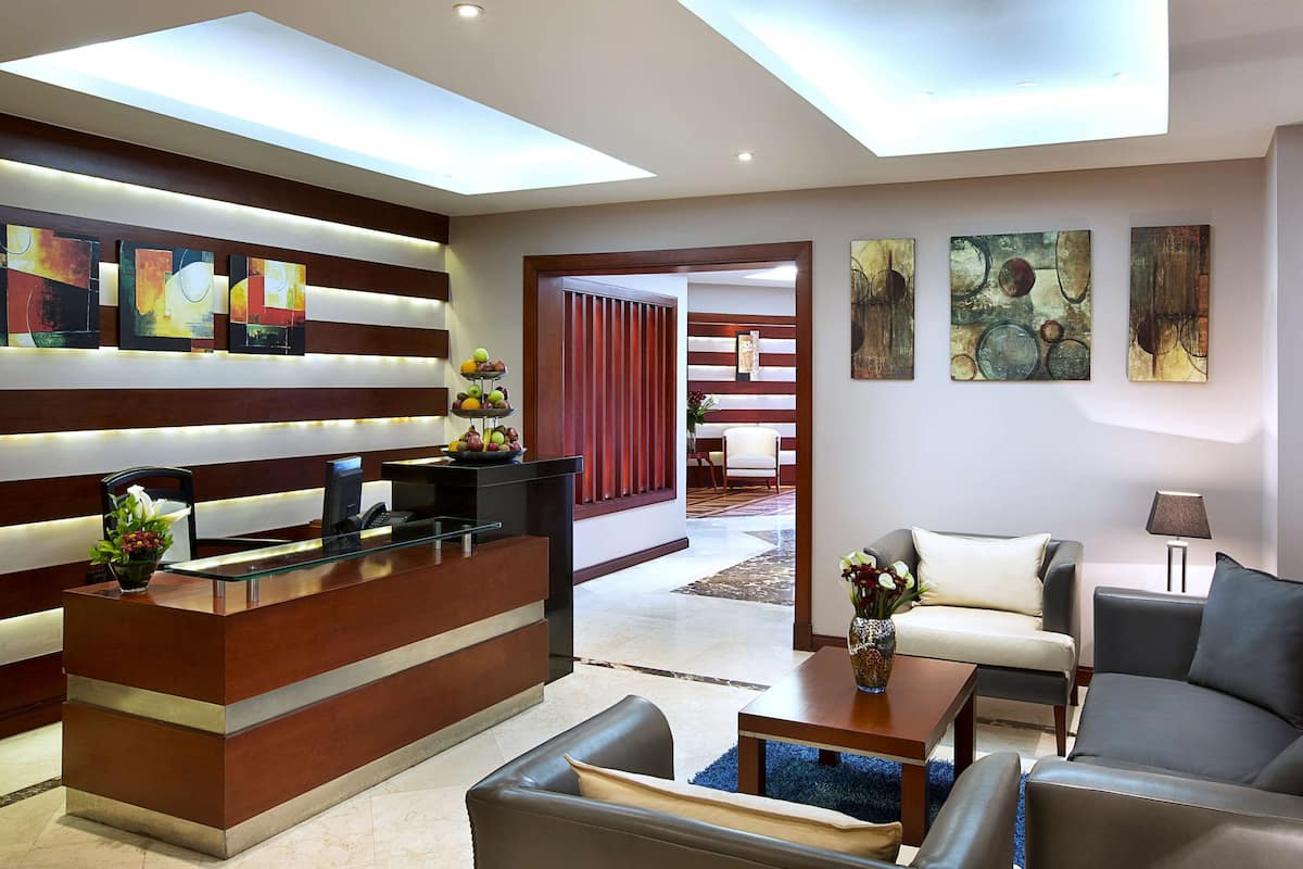 A modern hotel lobby with a reception desk, seating area, and artwork on the walls.