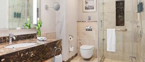 A modern bathroom with a marble sink, a glass-enclosed shower, and a toilet.