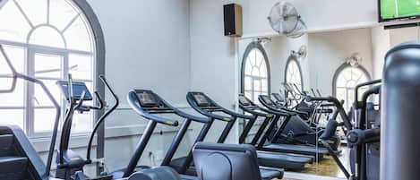 A gym with multiple treadmills, exercise bikes, and a large window providing natural light.