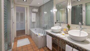 Un baño moderno con dos lavamanos, una bañera amplia y un box de ducha de cristal.