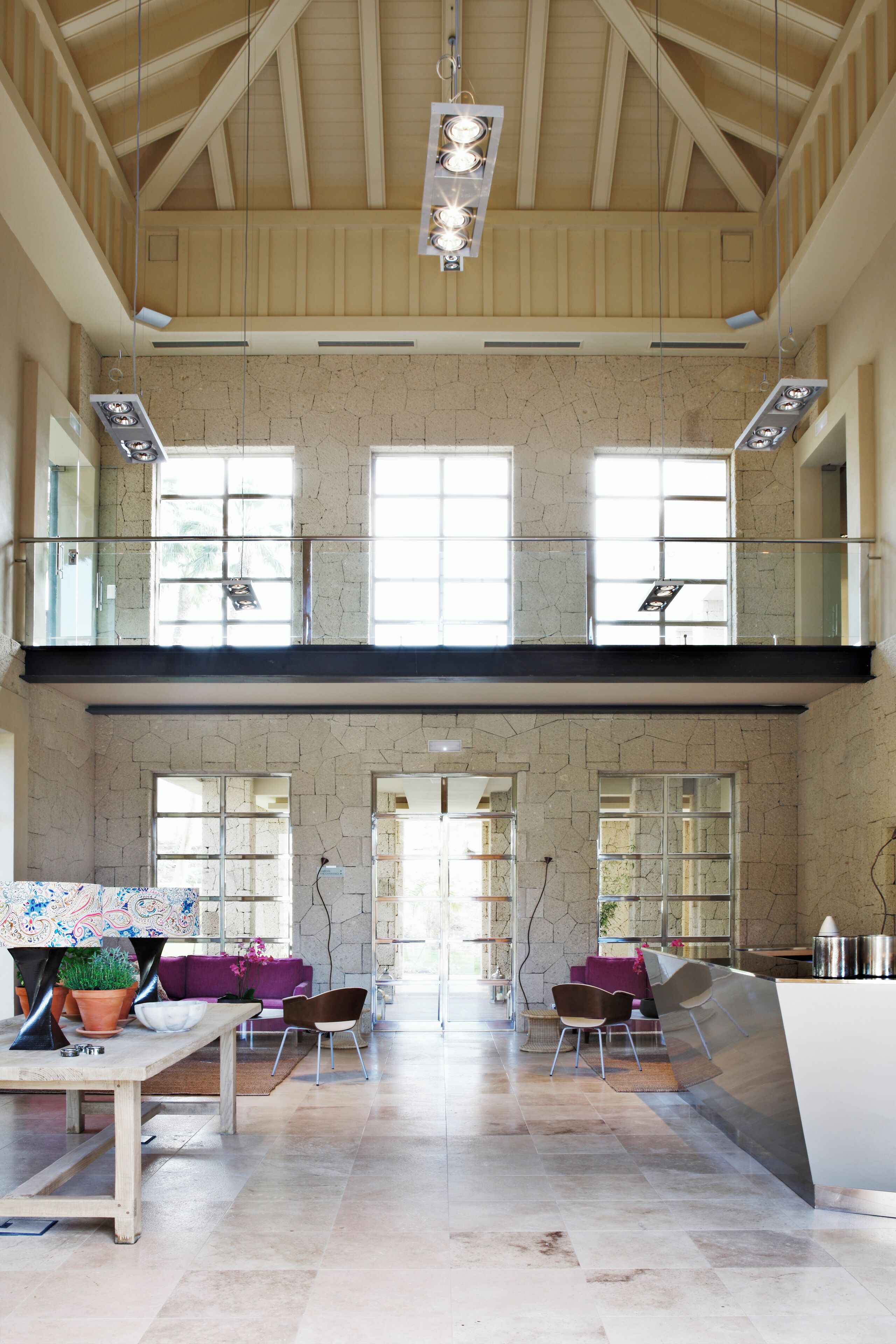 Een ruim interieur met een hoge plafon, grote ramen en een moderne keukenhoek.