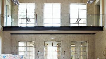 A spacious interior with a high ceiling, large windows, and a modern kitchen area.