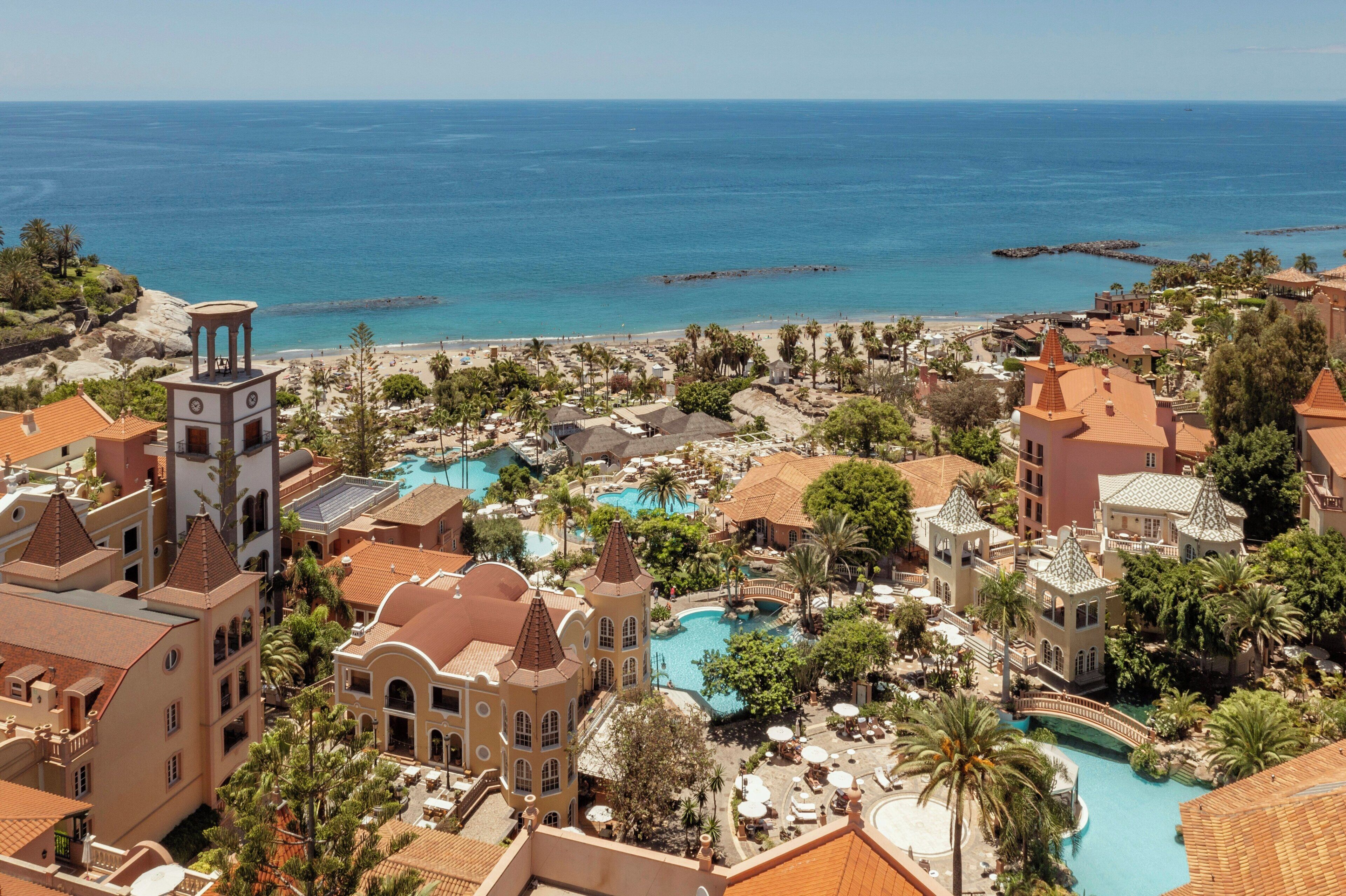A resort with a large pool, palm trees, and a view of the ocean.