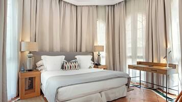 Un dormitorio con cama, mesitas de noche, un escritorio y cortinas.