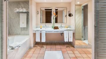 Un baño moderno con lavamanos de mármol, espejos dobles, ducha con puerta de cristal y suelo de baldosas.
