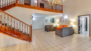 A spacious living area with a wooden staircase, a chandelier, and two sofas. - Rodeway Inn Red Oak (Red Oak)