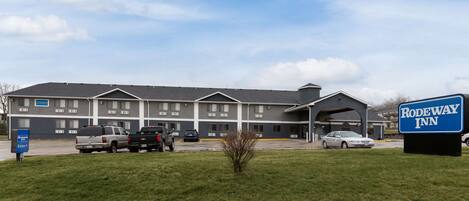 A Rodeway Inn with a parking lot, a grassy area, and a clear sky.