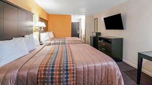 A hotel room with two beds, a TV mounted on the wall, a dresser, and a desk. - Rodeway Inn Red Oak (Red Oak)