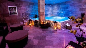 Un área de spa con piscina, paredes de piedra, asientos e iluminación ambiental.