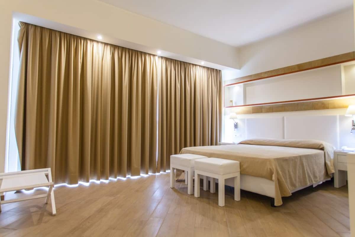 A modern bedroom with a large bed, a bedside table, a nightstand, and a bench.
