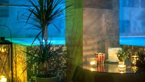 Una habitación con una planta grande en maceta, una mesa con velas y vistas al océano a través de una ventana.