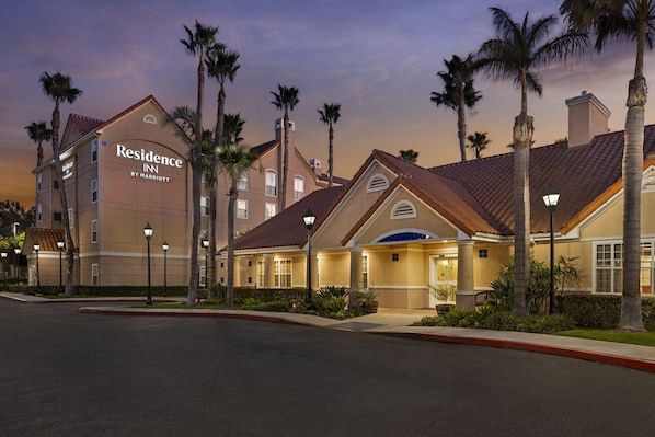 A hotel with a prominent sign, multiple floors, and a well-maintained exterior with palm trees.