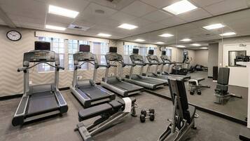 A gym with treadmills, dumbbells, and exercise equipment.