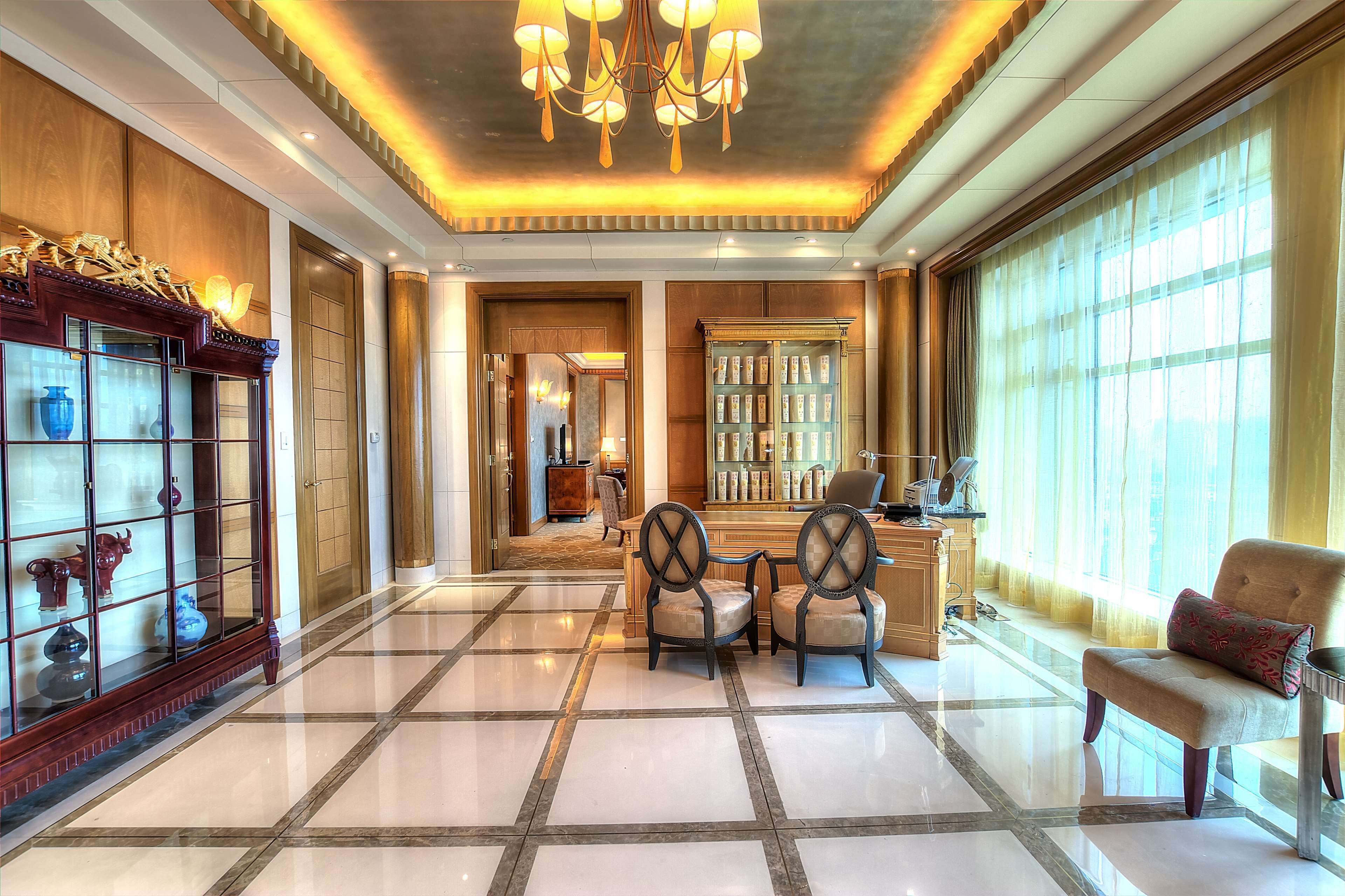 A spacious lobby with a polished marble floor, a chandelier, and a seating area with chairs and a sofa.