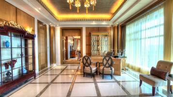 A spacious lobby with a polished marble floor, a chandelier, and a seating area with chairs and a sofa.