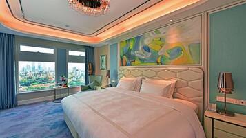 A modern hotel room with a large bed, a city view, a unique abstract painting, and a chandelier.