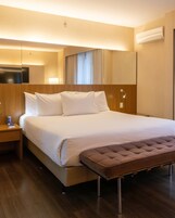 Una camera d'albergo con un letto grande, una testiera in legno, un comodino con una lampada e un condizionatore d'aria a parete.