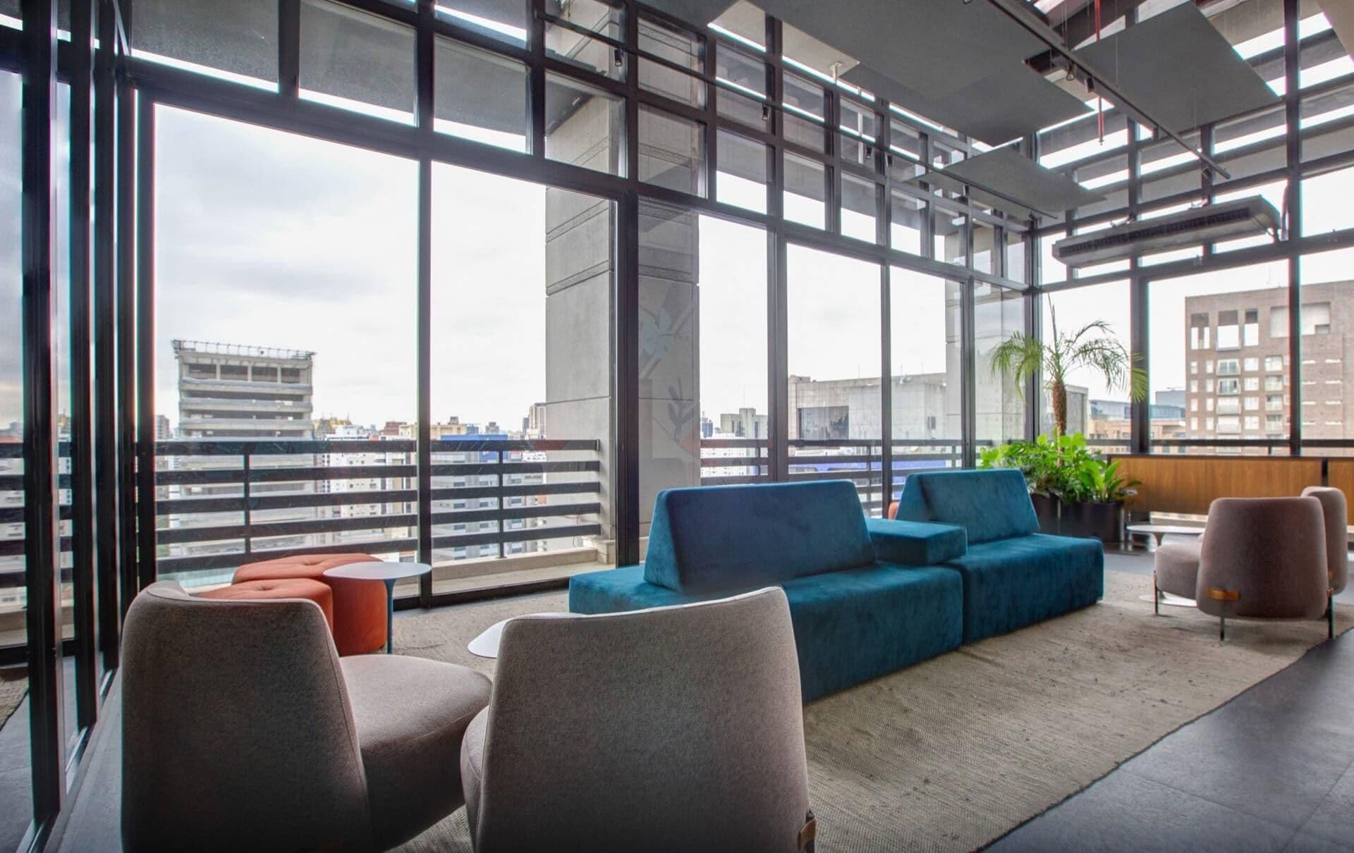 Eine moderne Lounge mit großen Fenstern, einem blauen Sofa und einem kleinen Tisch.