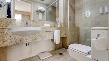 Un baño moderno con lavamanos de granito, cabina de ducha de vidrio y un inodoro.