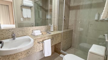 Un baño moderno con lavabo, espejo, inodoro y ducha de vidrio.