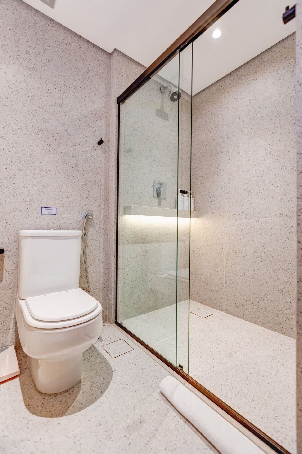 Une salle de bain moderne avec des toilettes, une douche à parois de verre et un sol en marbre.