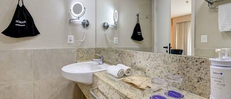 A bathroom with a sink, mirror, towel rack, and toiletries on the counter.