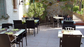 An outdoor dining area with wicker chairs and tables, surrounded by stone walls and potted plants. - Le Relais du Val d'Orbieu (Ornaisons)