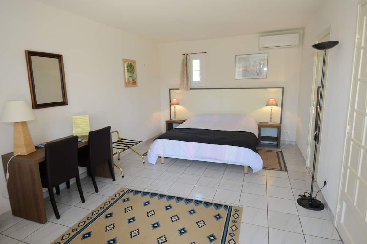 A hotel room with a bed, desk, chairs, a lamp, and a floor lamp.
