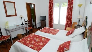 A hotel room with two beds, a desk, a chair, a television, and a lamp. - Le Relais du Val d'Orbieu (Ornaisons)