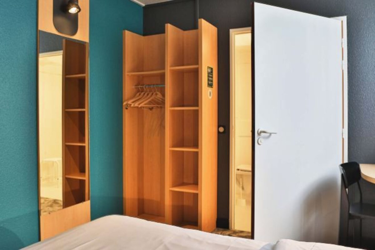 Een slaapkamer met een bed, een kledingkast en een bureau met een stoel.