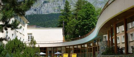 A pool area with lounge chairs, a stone wall, and a mountain backdrop.