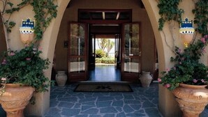 An entrance with an arched doorway, potted plants, and a tiled floor. - King's Residence Hotel (Centola)