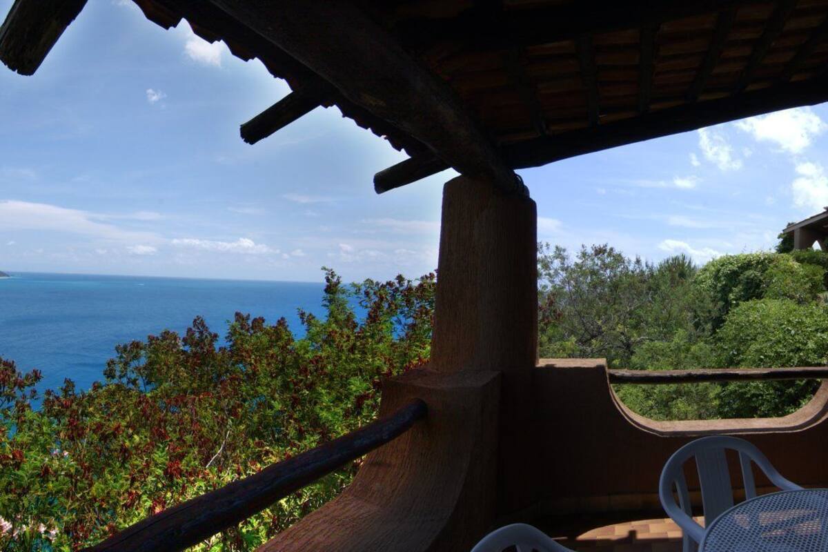 Un balcone con vista sul mare, un letto e un tavolino.