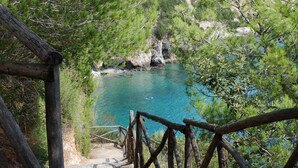 A wooden staircase leading to a coastal area with clear blue water and rocky cliffs. - King's Residence Hotel (Centola)