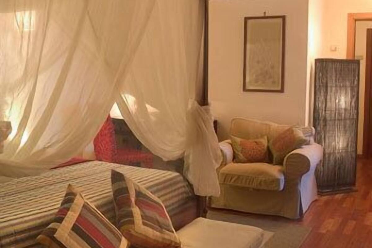 Una camera da letto con un letto, una sedia e un comodino.