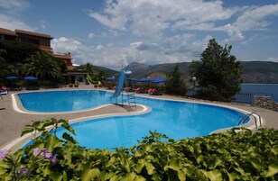 Una piscina al aire libre, sombrillas, sillones reclinables de piscina