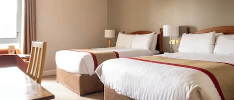 A hotel room with two beds, a desk, and a chair.