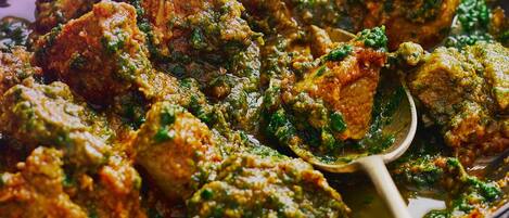 A close-up of a dish with chunks of meat in a thick, green sauce.